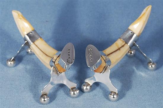 A pair of silver mounted boar tusk knife rests, by Army & Navy Co-Operative Society Ltd, Length 90mm.